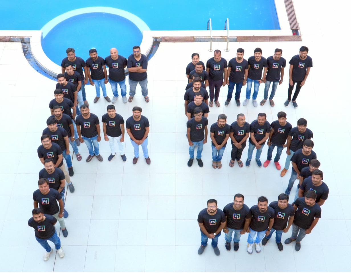 F5 team members in branded shirts standing in the shape of the letters F5, photographed from above.